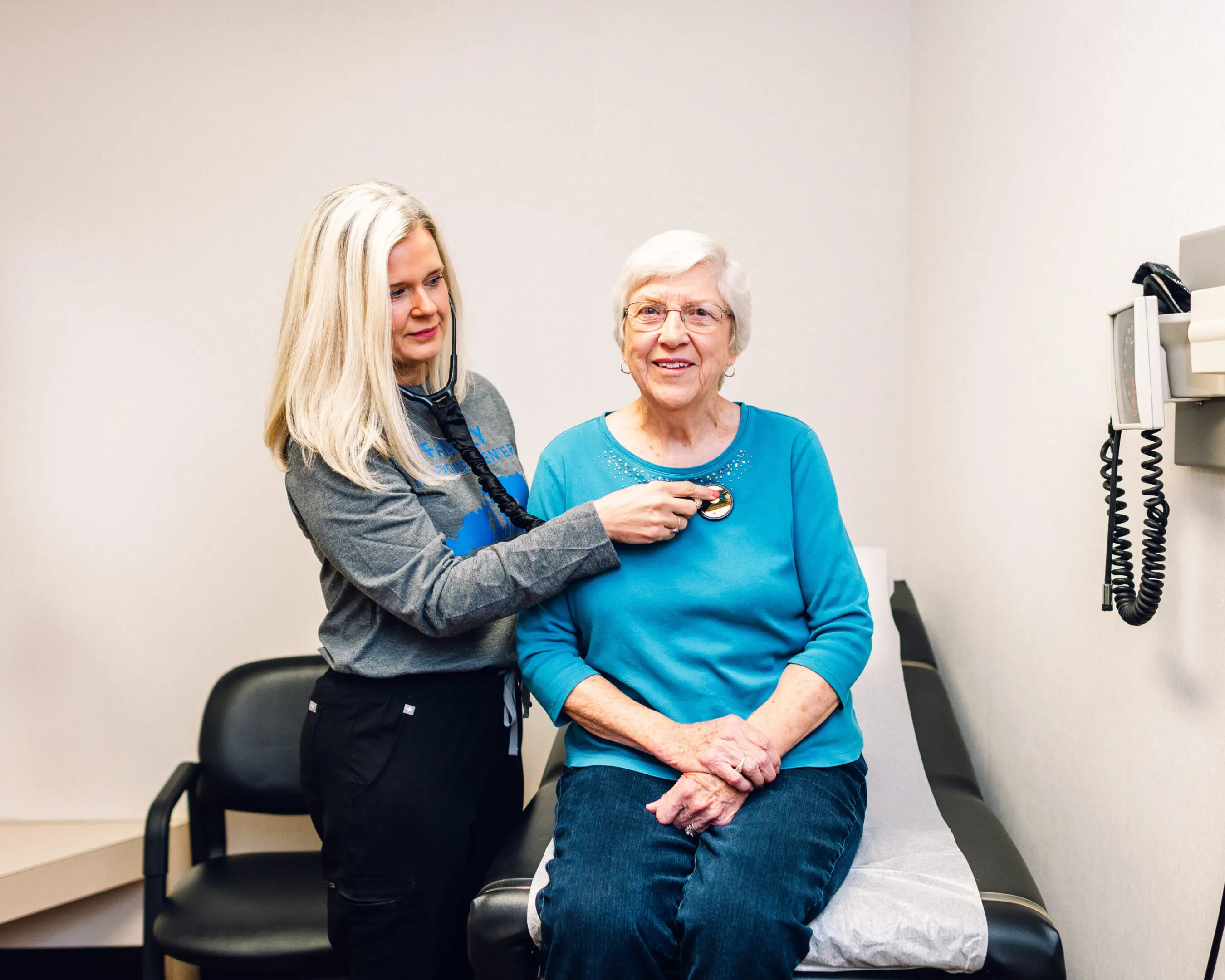 A woman assists an elderly woman during a medical check-up.