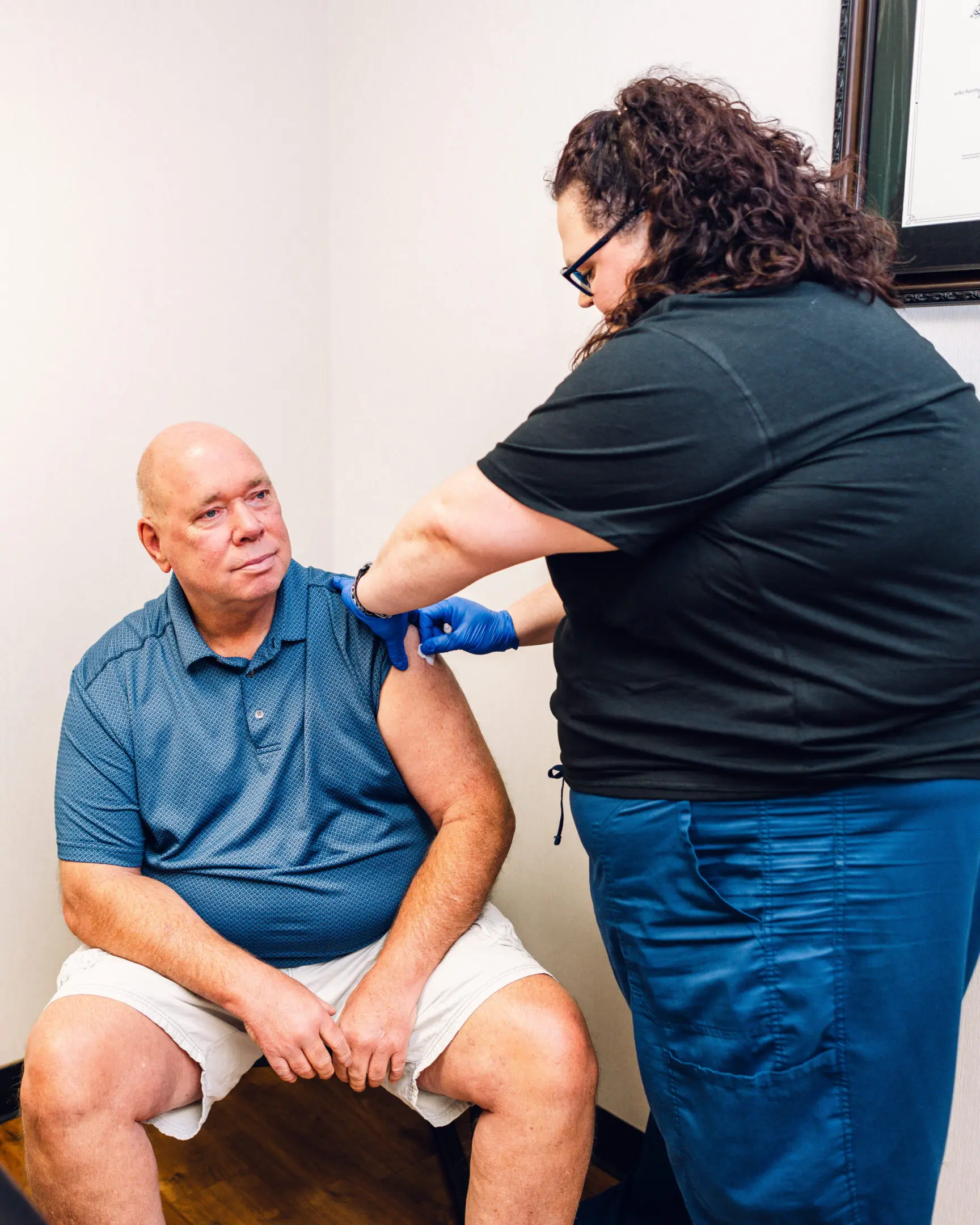 Healthcare worker administering a vaccine to an elderly man.