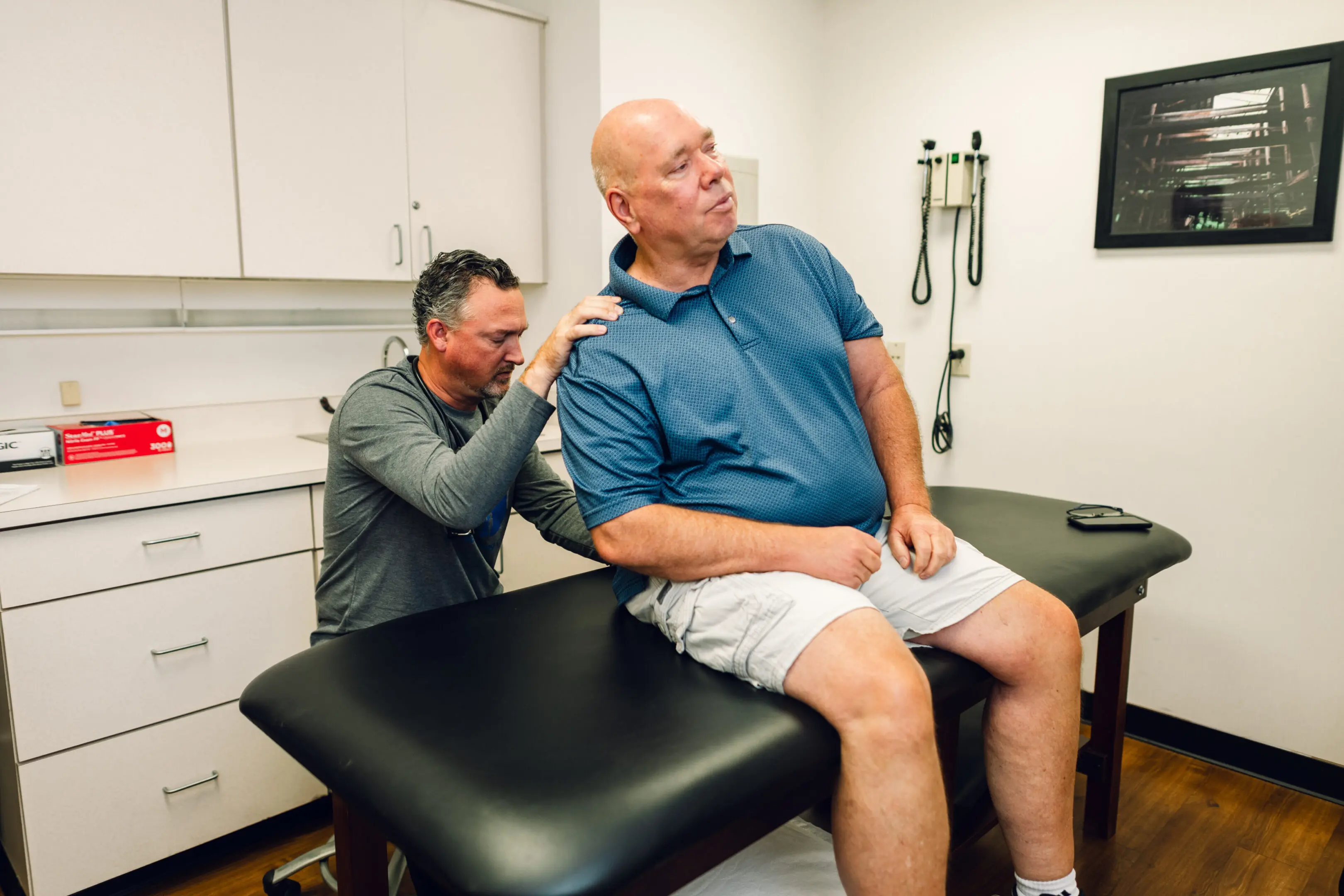 Doctor examining patient's neck in a clinic room.