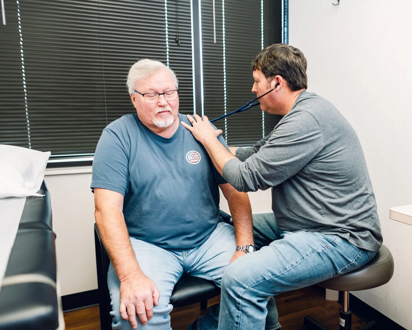 Doctor examining an elderly man's chest with a stethoscope.