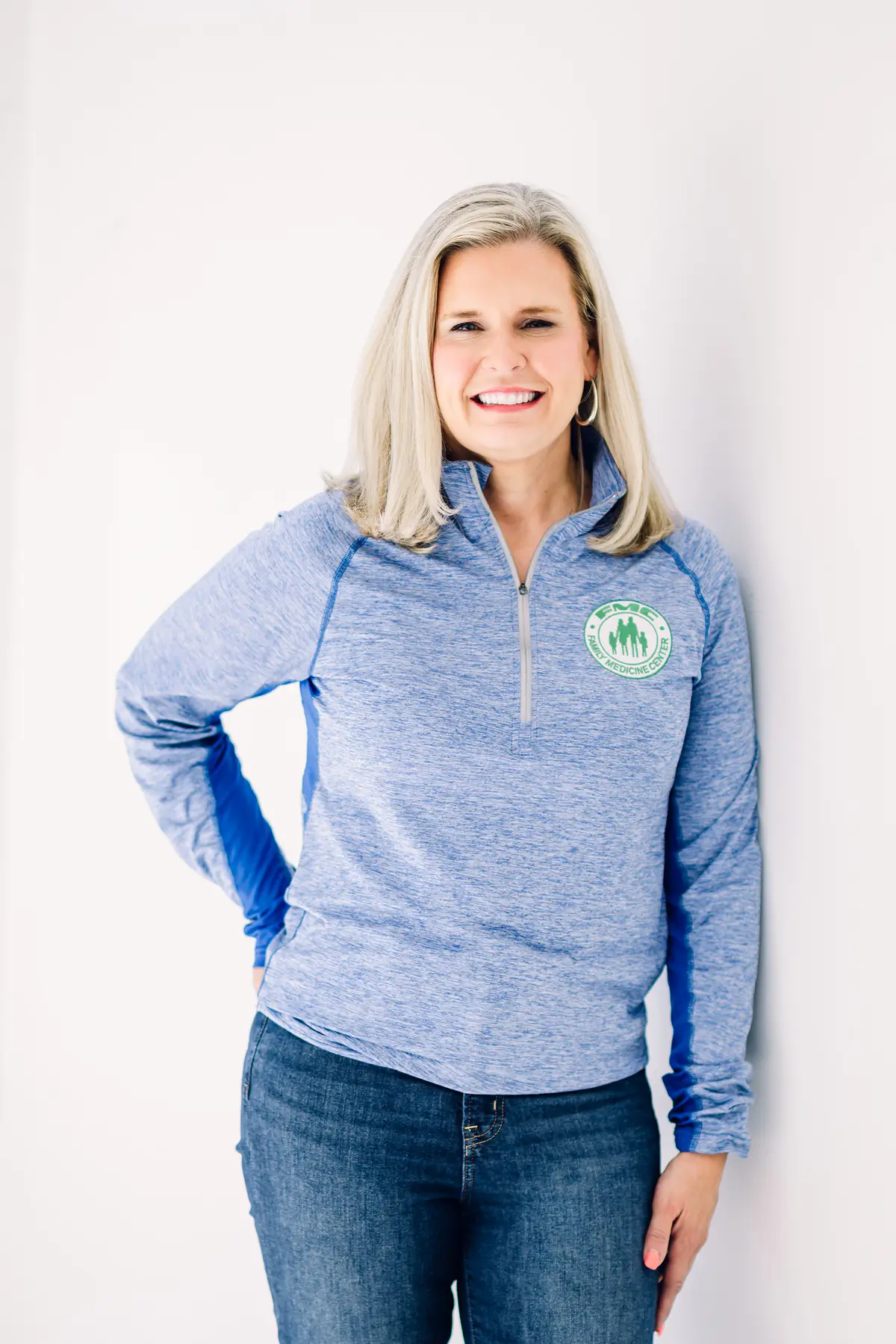 Smiling woman in blue quarter-zip sweater.
