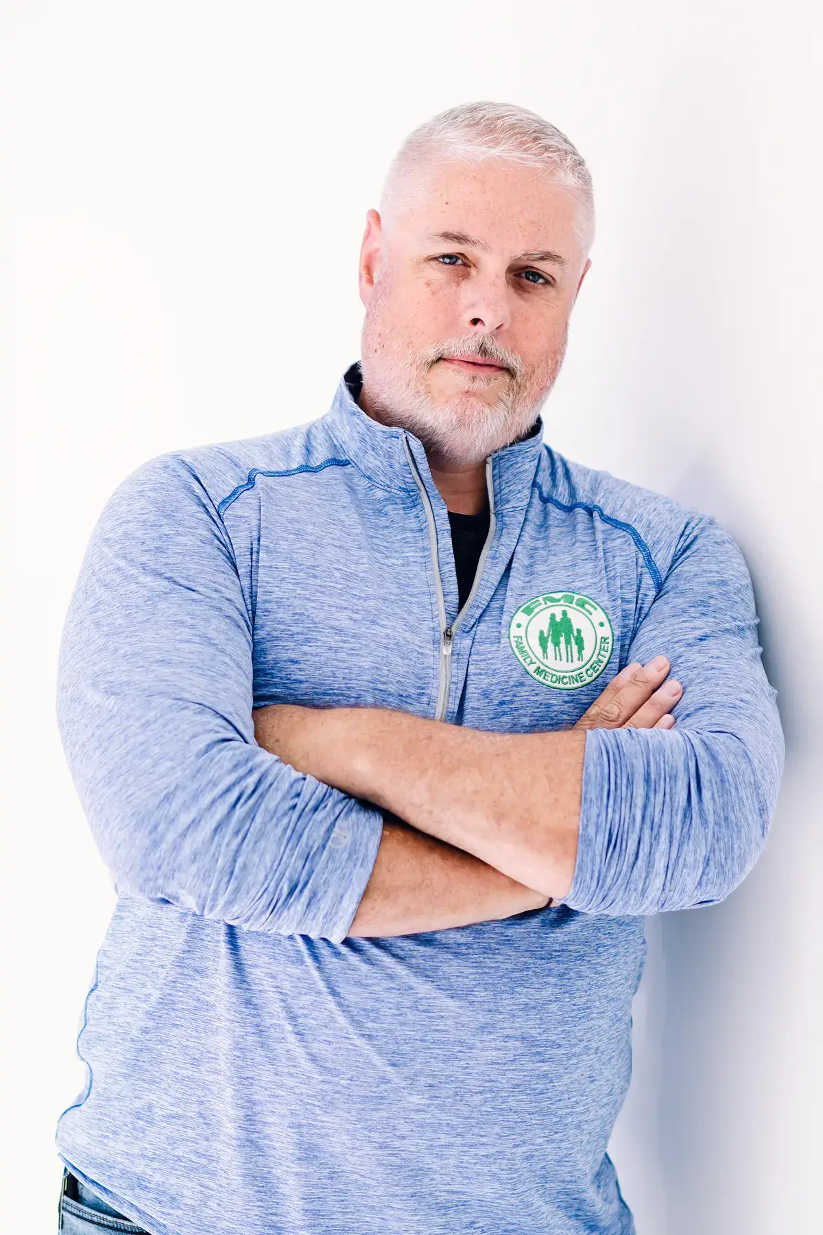 Man in blue shirt with crossed arms.