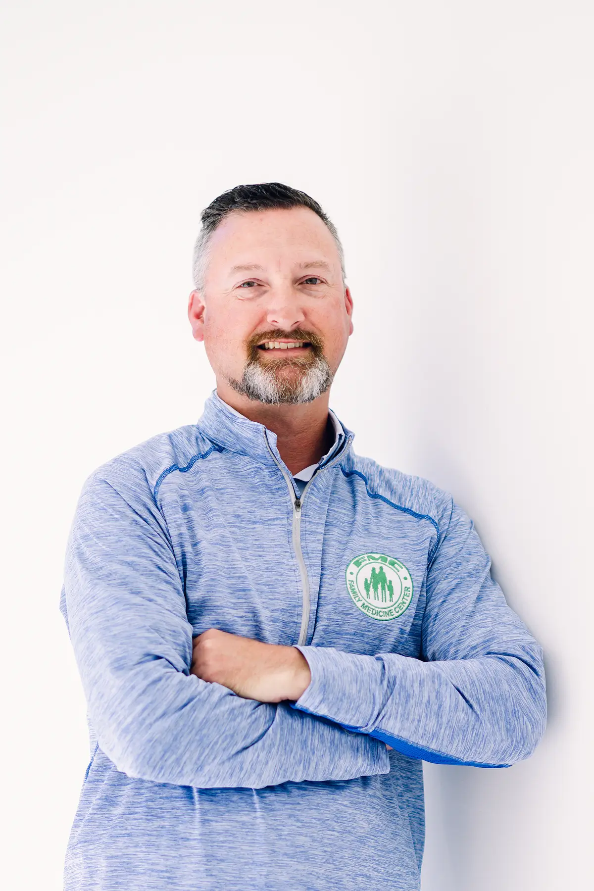 Man in blue sweater, arms crossed, smiling.